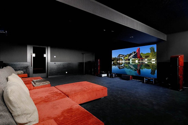 orange-lounge-chairs-and-grey-cushions-facing-large-screen-in-home-theater-studio.jpg